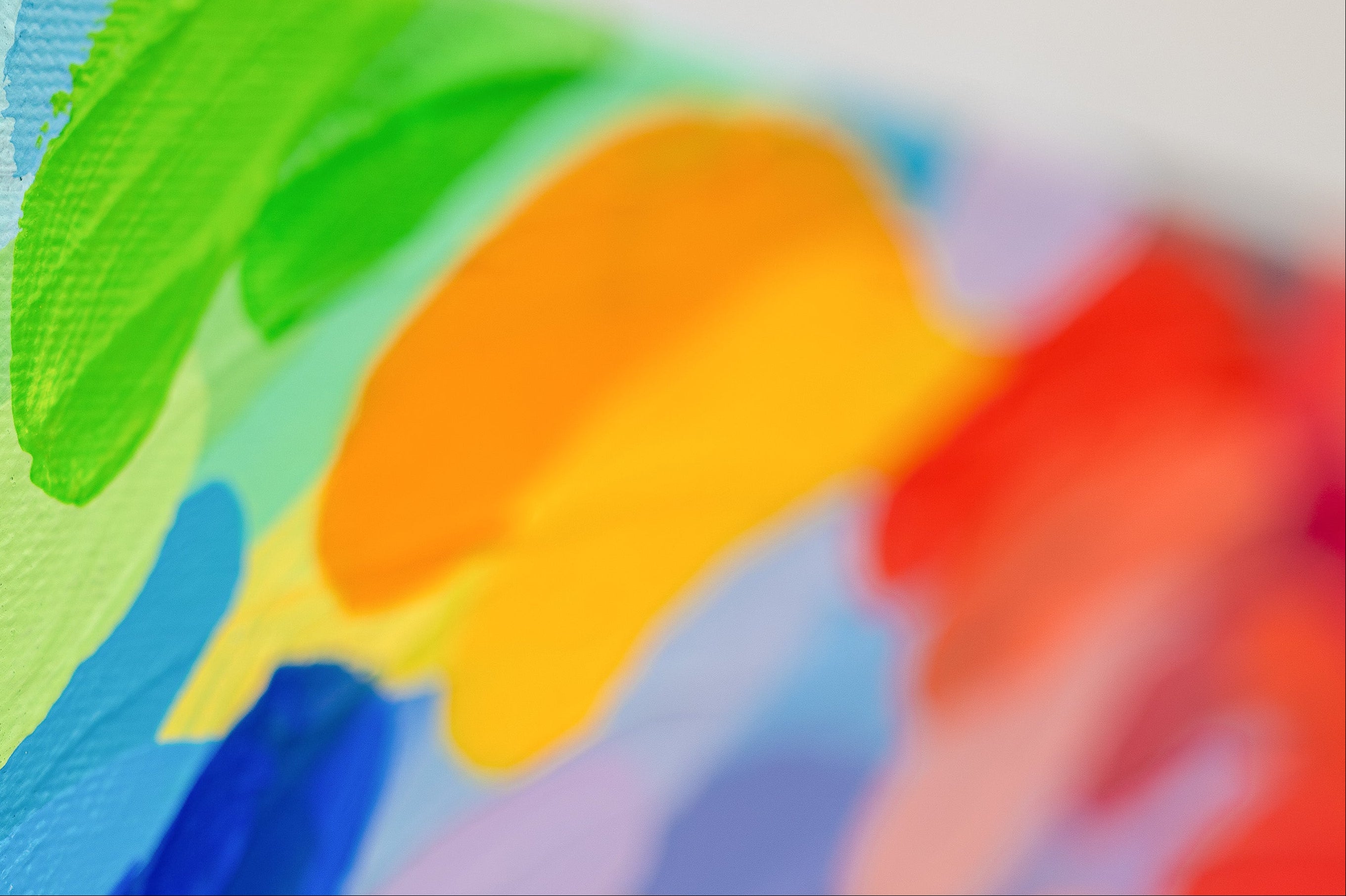 Close-up of a colorful painting with blue, green, orange, and red strokes on a textured surface.