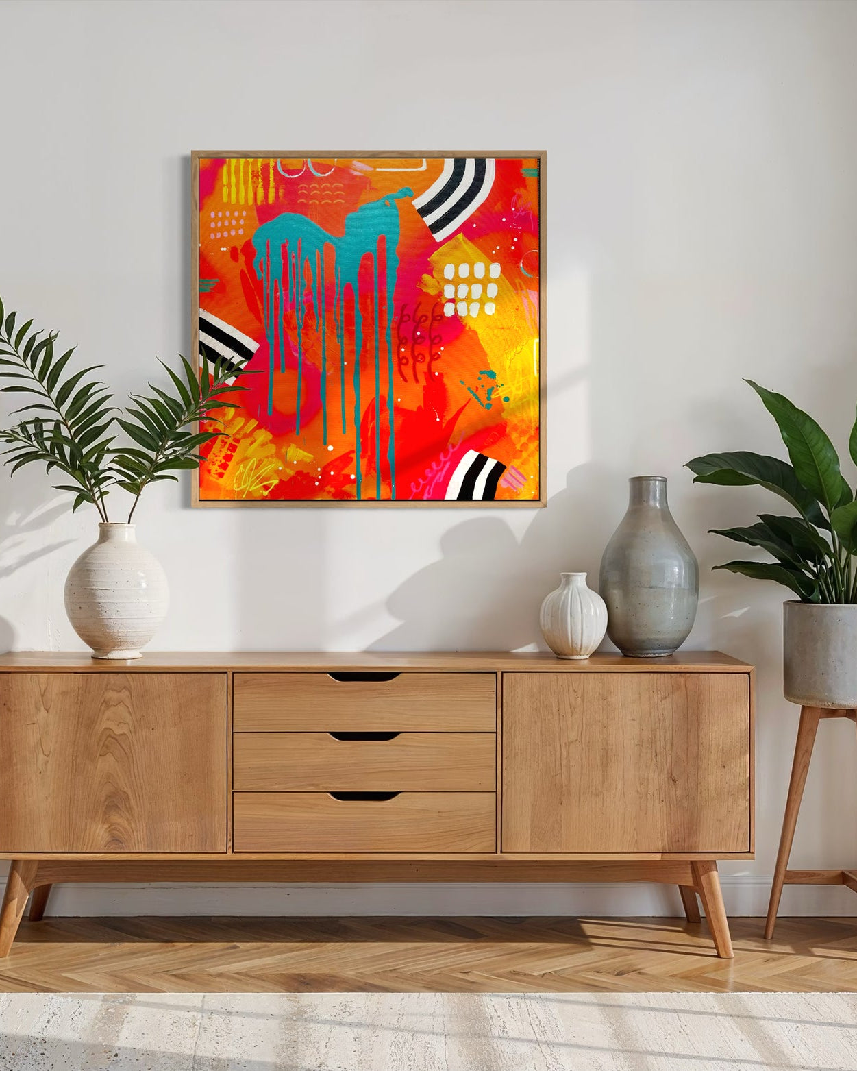 Modern living room with wooden sideboard, abstract painting, and potted plants.